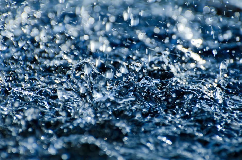 Close-up of water droplets splashing, capturing motion and energy in blue tones.