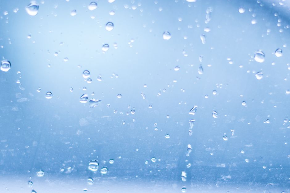 Close-up of raindrops on a clear glass surface, creating a calm abstract pattern.