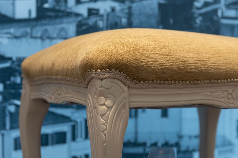 Vintage white wooden stool with details and soft seat in apartment with picture of city on wall