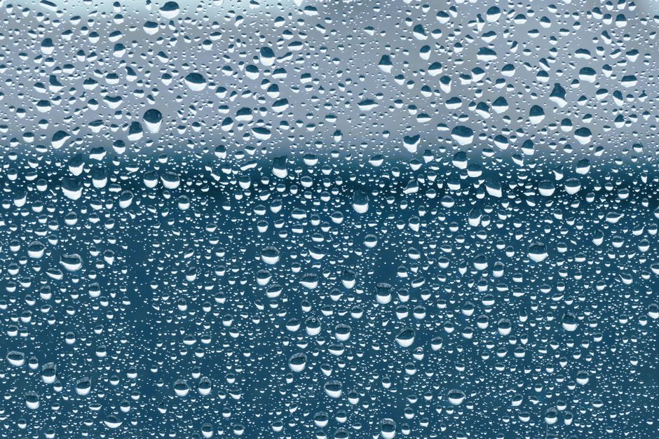 Detailed view of water droplets on a glass window during a rainstorm.